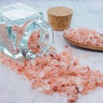 A closeup shot of a jar and a wooden spoon with pink sea salt