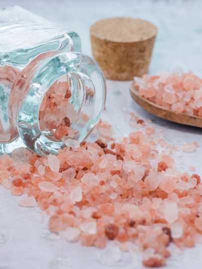 A closeup shot of a jar and a wooden spoon with pink sea salt